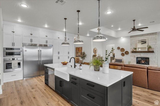 kitchen featuring white cabinets, visible vents, appliances with stainless steel finishes, a sink, and open floor plan