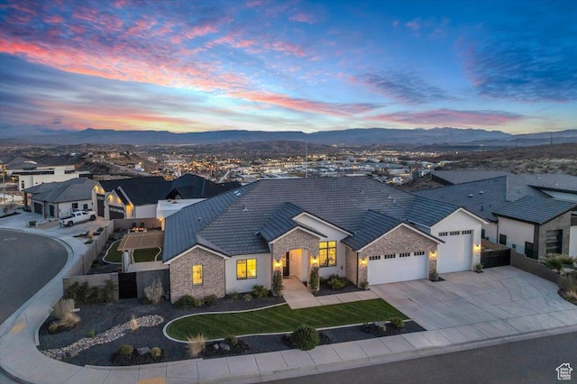 view of front of house with a mountain view, stone siding, a tile roof, an attached garage, and concrete driveway