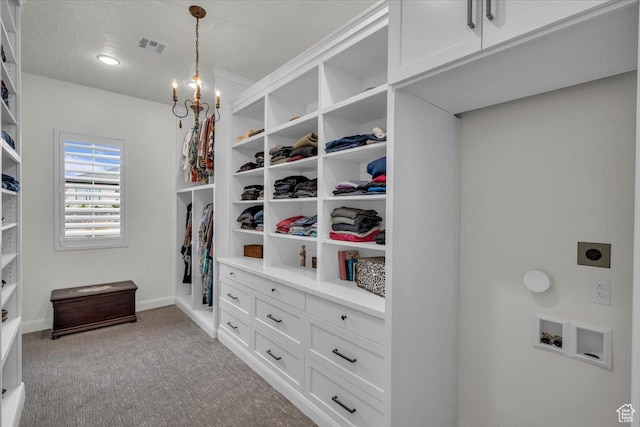 walk in closet featuring light carpet, an inviting chandelier, and visible vents