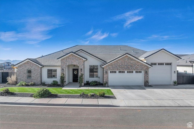 view of front of home with a tiled roof, an attached garage, concrete driveway, brick siding, and stucco siding