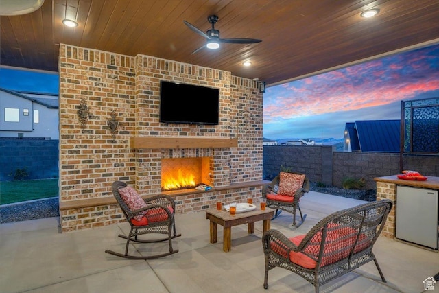 view of patio featuring a ceiling fan, an outdoor brick fireplace, and fence