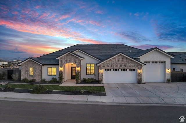 view of front of house featuring concrete driveway, stucco siding, an attached garage, a tile roof, and a lawn