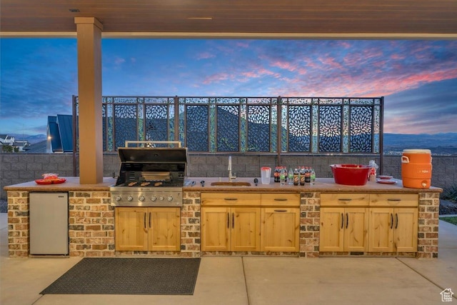 patio terrace at dusk with a grill and exterior kitchen