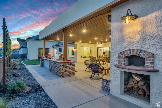 view of patio featuring fence, an outdoor kitchen, grilling area, and an outdoor fireplace