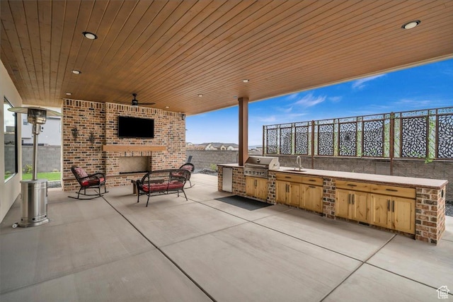 view of patio with an outdoor brick fireplace, an outdoor kitchen, ceiling fan, a grill, and a sink