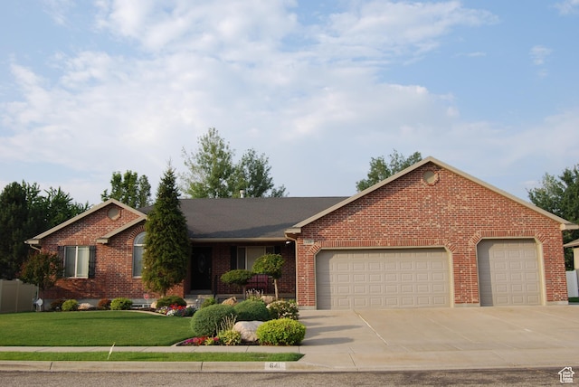 single story home with a garage, concrete driveway, a front yard, and brick siding