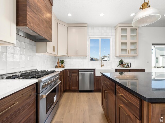 kitchen featuring stainless steel appliances, white cabinetry, a sink, and custom range hood