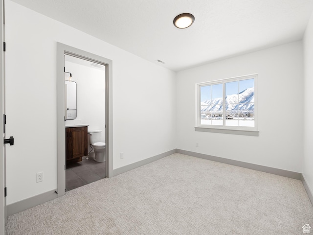 unfurnished bedroom with carpet, visible vents, baseboards, and ensuite bathroom