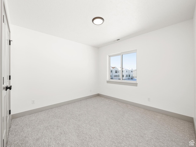 carpeted empty room featuring baseboards and visible vents