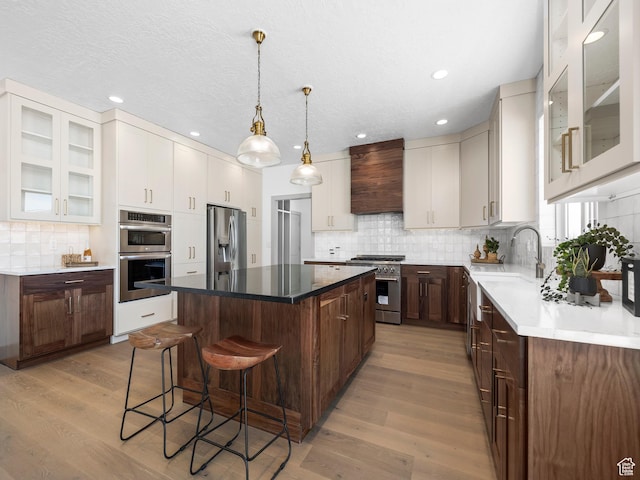 kitchen featuring a breakfast bar, light wood-type flooring, premium range hood, stainless steel appliances, and a kitchen island