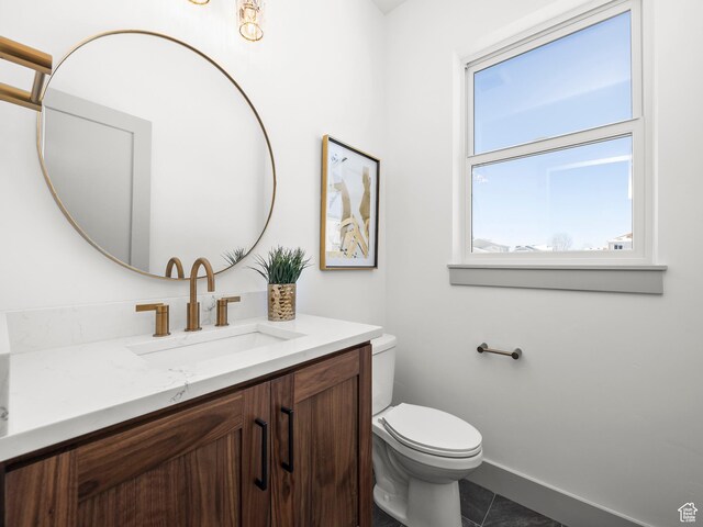 half bath featuring toilet, tile patterned floors, vanity, and baseboards