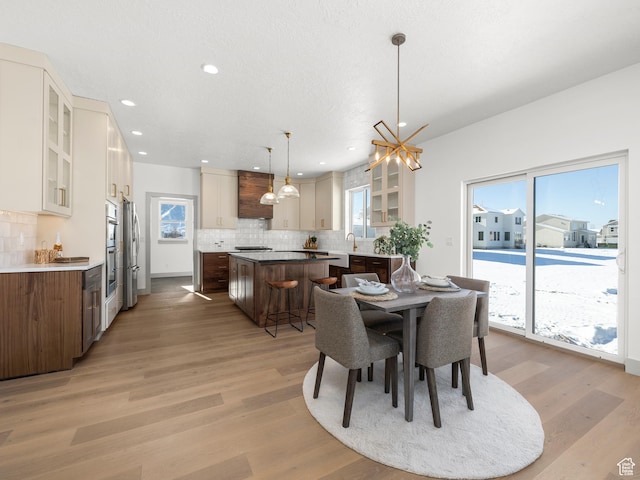 dining area featuring light wood finished floors, an inviting chandelier, recessed lighting, and a wealth of natural light