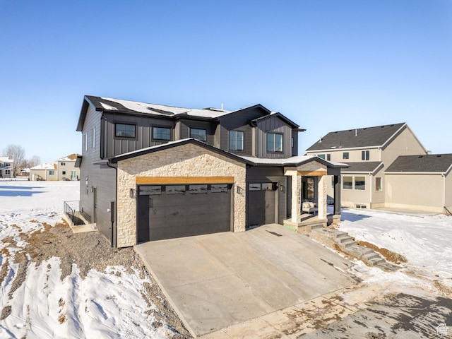 view of front facade with an attached garage, board and batten siding, driveway, and stone siding