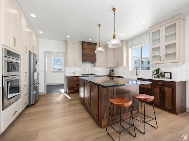 kitchen with custom range hood, a center island, a breakfast bar area, appliances with stainless steel finishes, and a sink