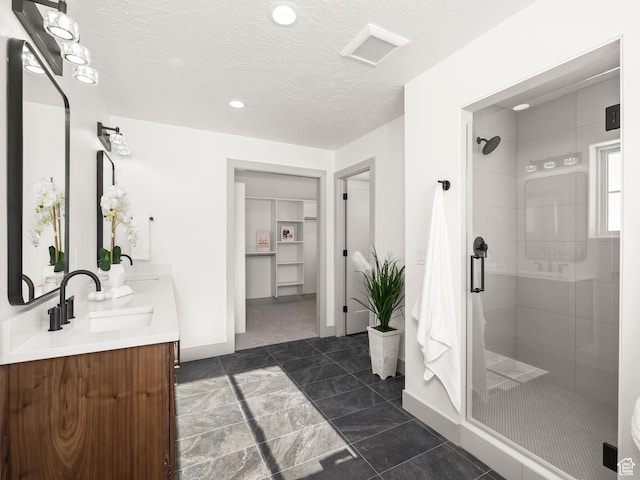 bathroom featuring double vanity, a stall shower, a textured ceiling, visible vents, and a sink