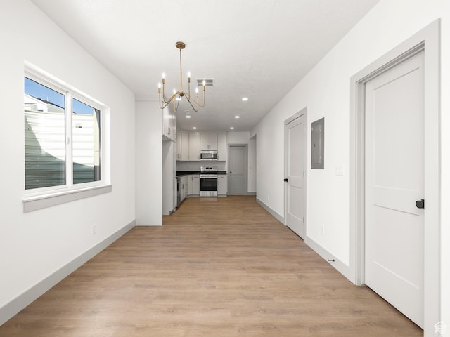 interior space with light wood-type flooring, electric panel, visible vents, a chandelier, and appliances with stainless steel finishes