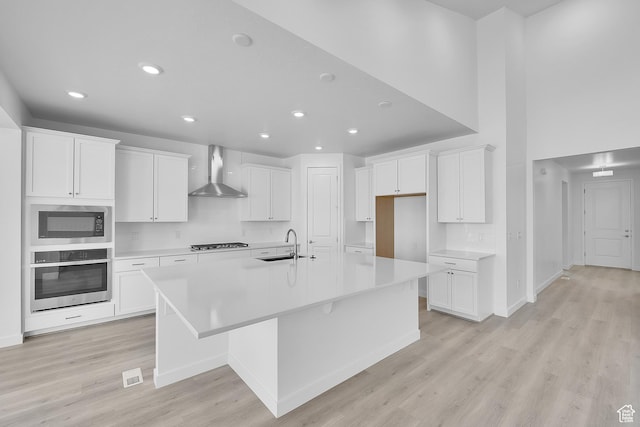 356 W Emma St Unit 625, Grantsville, UT 84029 - kitchen featuring wall chimney exhaust hood, a sink, light wood finished floors, a spacious island, and stainless steel appliances