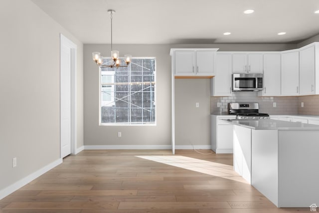 6658 W Spring Snow Ln, Herriman, UT 84096 - kitchen featuring tasteful backsplash, a chandelier, white cabinetry, appliances with stainless steel finishes, and light wood finished floors