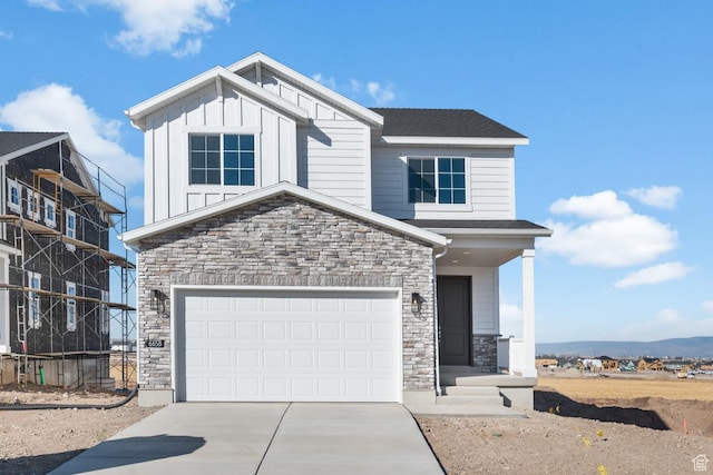 view of front of property with board and batten siding, concrete driveway, and stone siding