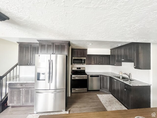 2770 S 9500 E, Jensen, UT 84035 - kitchen featuring a sink, appliances with stainless steel finishes, dark brown cabinetry, wood finished floors, and backsplash