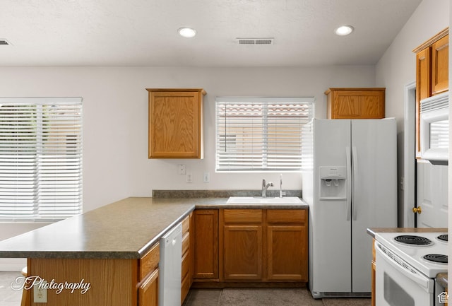 1360 E Telegraph St # 8, Washington, UT 84780 - kitchen with white appliances, brown cabinetry, a peninsula, visible vents, and a sink