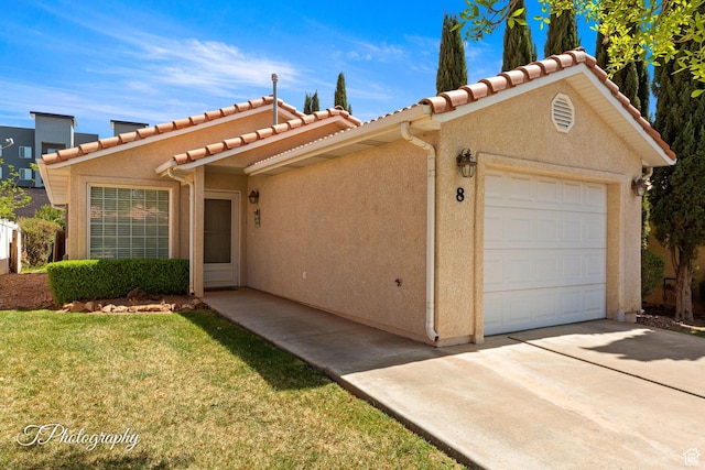 view of front of house with concrete driveway, a front yard, stucco siding, and a garage