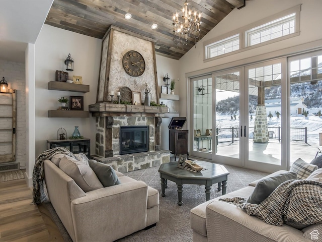 living room featuring visible vents, wood finished floors, a stone fireplace, high vaulted ceiling, and a notable chandelier