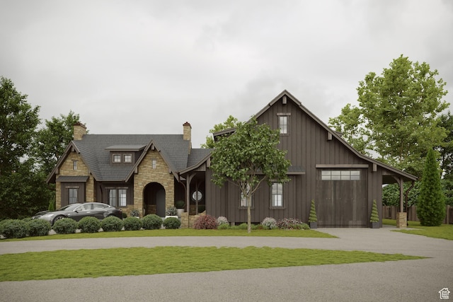 view of front of house with a chimney, board and batten siding, a front yard, and stone siding