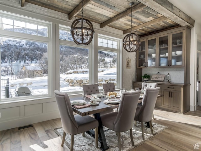 dining space featuring an inviting chandelier, beam ceiling, a wealth of natural light, and wooden ceiling