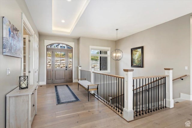 foyer entrance featuring an inviting chandelier, baseboards, and light wood finished floors