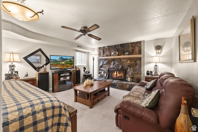 living area with a textured ceiling, light colored carpet, a ceiling fan, a stone fireplace, and visible vents