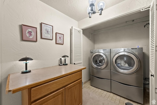 laundry room featuring a textured wall, washing machine and clothes dryer, laundry area, and a textured ceiling