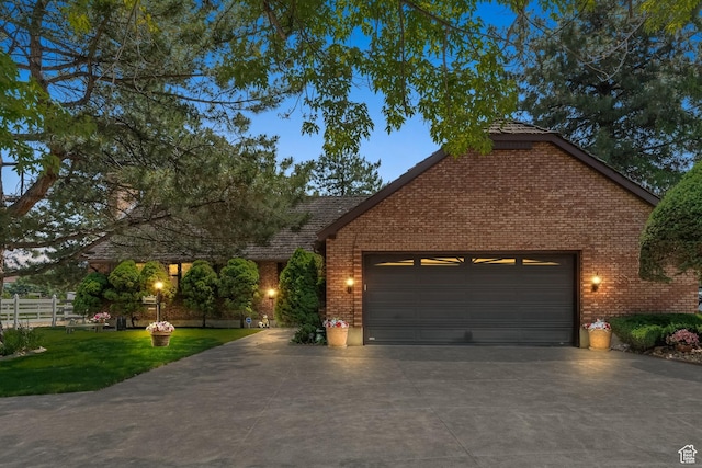 view of front of property featuring an attached garage, fence, concrete driveway, brick siding, and a front lawn