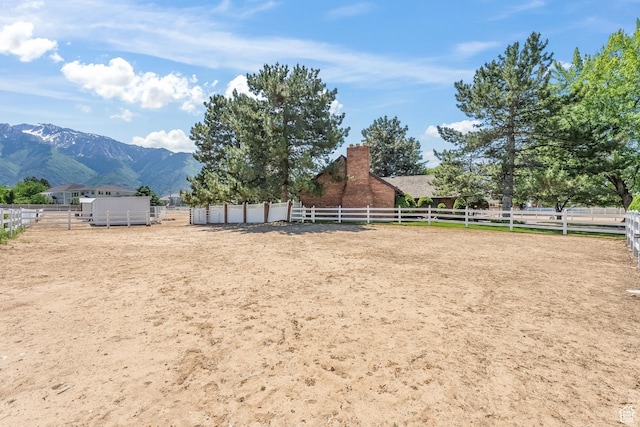 view of yard with a rural view, a mountain view, and an enclosed area