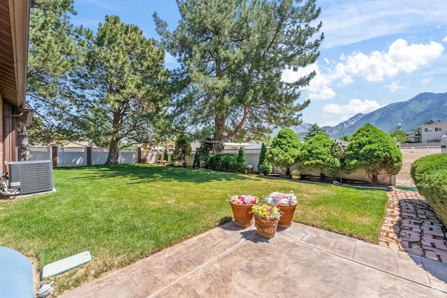 view of yard with central air condition unit, a mountain view, a fenced backyard, and a patio area
