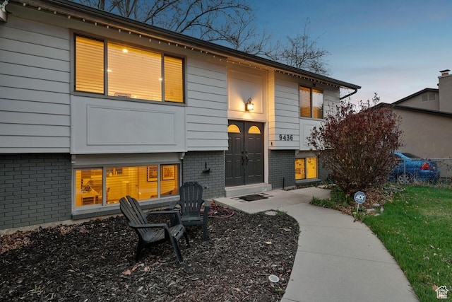 back of property at dusk featuring brick siding