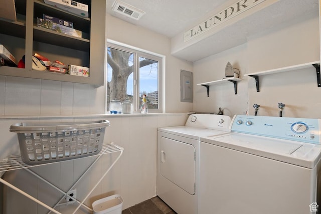 laundry room featuring electric panel, a wainscoted wall, visible vents, laundry area, and washing machine and clothes dryer