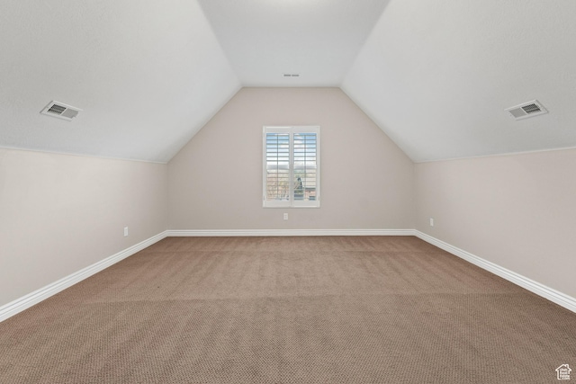 additional living space with carpet flooring, baseboards, lofted ceiling, and visible vents