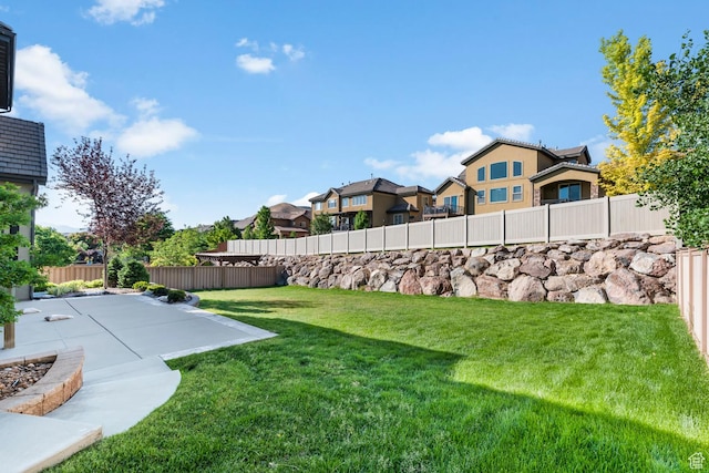 view of yard with a fenced backyard, a residential view, and a patio
