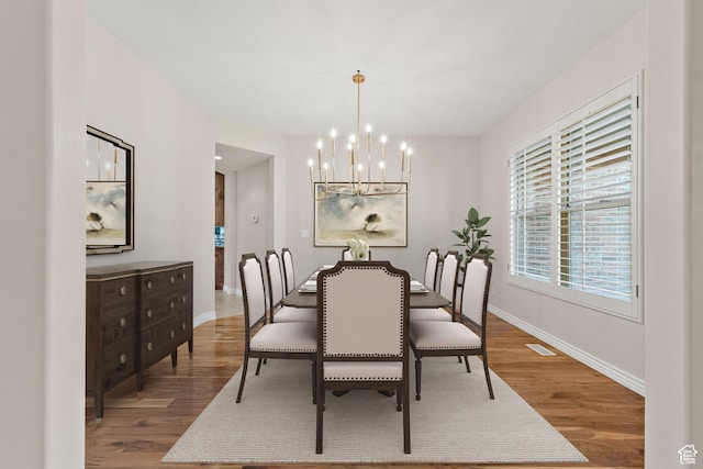 dining space with baseboards, an inviting chandelier, and wood finished floors