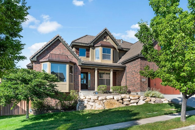 craftsman-style house featuring brick siding, a front lawn, fence, and stucco siding
