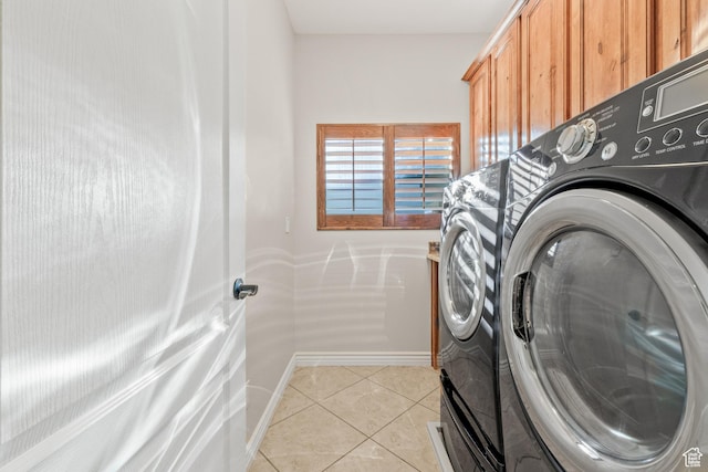 clothes washing area with cabinet space, light tile patterned floors, baseboards, and washer and dryer