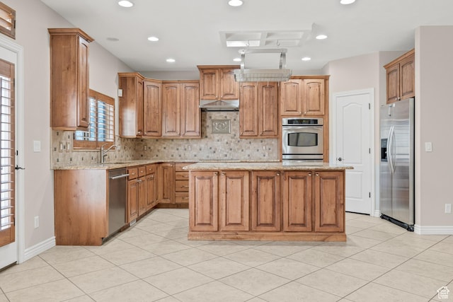 kitchen featuring under cabinet range hood, tasteful backsplash, a kitchen island, and appliances with stainless steel finishes