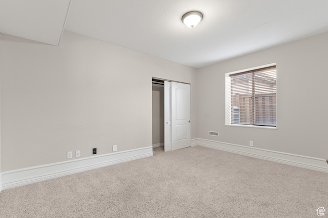 unfurnished bedroom with a closet, visible vents, light colored carpet, and baseboards