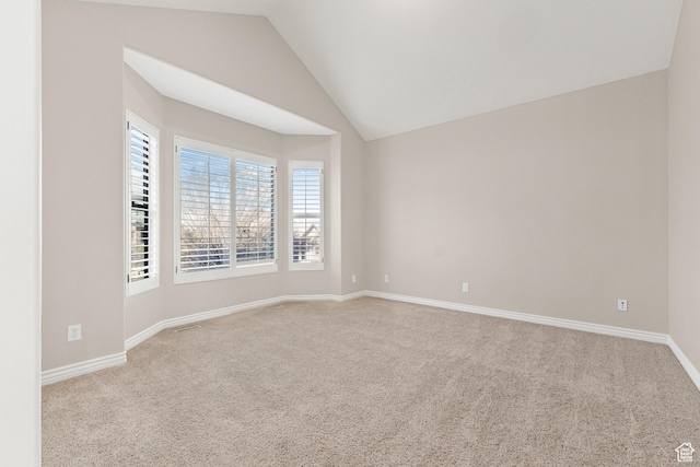spare room featuring carpet flooring, baseboards, and lofted ceiling