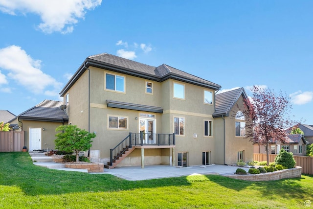 back of property featuring a tiled roof, a yard, stucco siding, a patio area, and fence