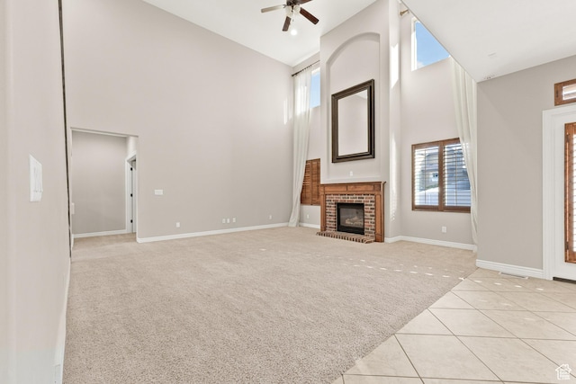 unfurnished living room featuring baseboards, light tile patterned floors, a ceiling fan, high vaulted ceiling, and light colored carpet