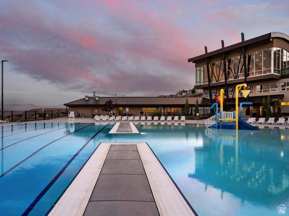 community pool with fence, a patio area, and a water play area