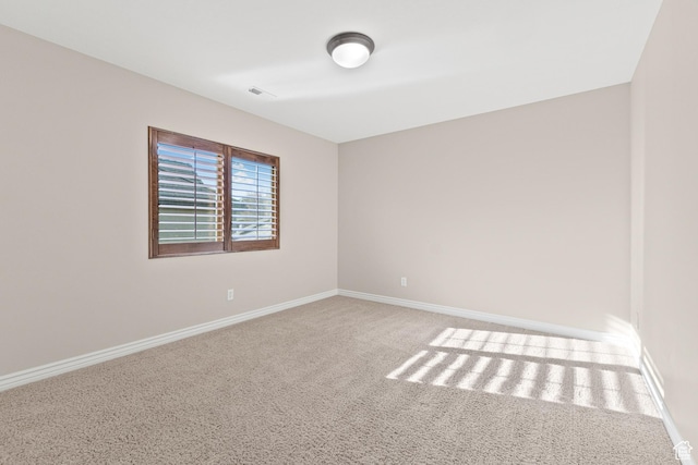carpeted spare room with visible vents and baseboards