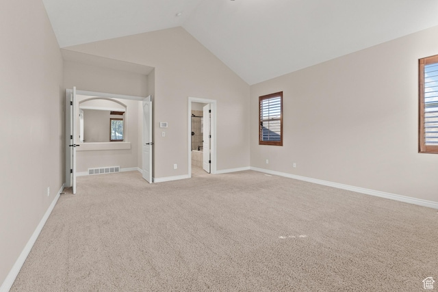 unfurnished bedroom featuring light carpet, high vaulted ceiling, baseboards, and visible vents